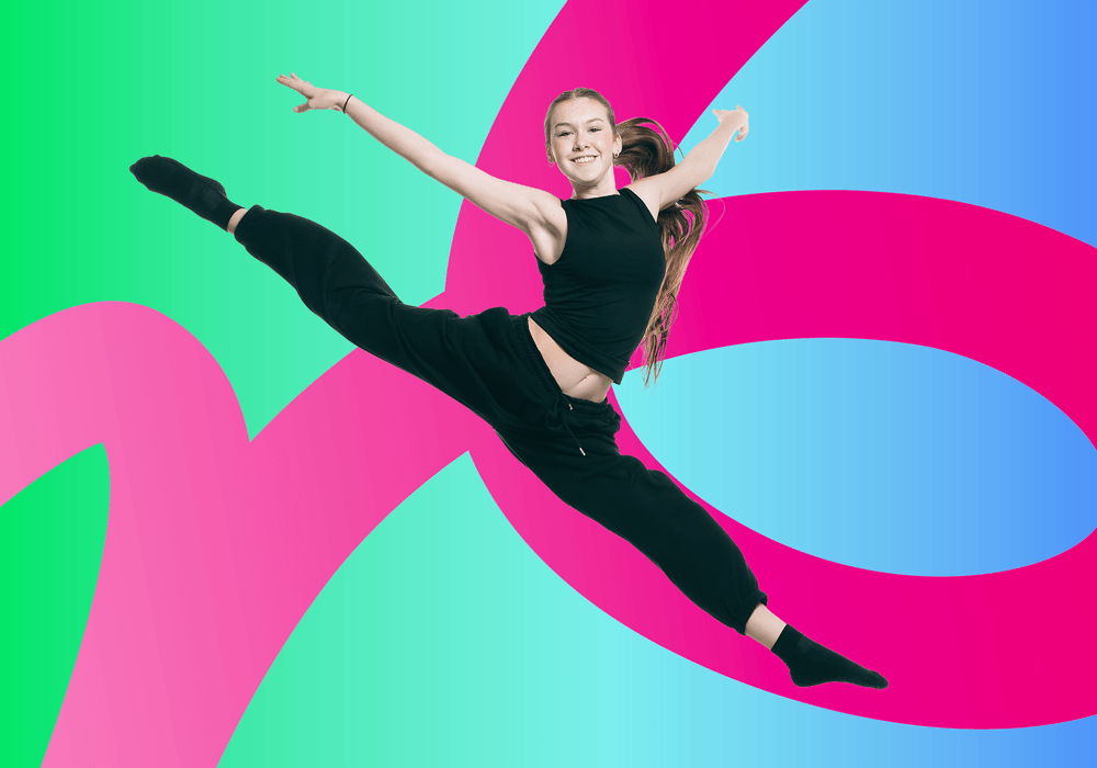 Young woman in a black outfit leaps mid air with a joyful smile against a bright abstract gradient background with large pink curves