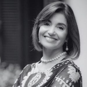 Portrait of a smiling woman wearing a pearl necklace and floral patterned blouse looking at the camera