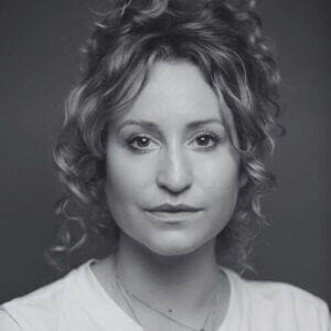 Black and white portrait of a woman with short curly hair looking at the camera with a neutral expression