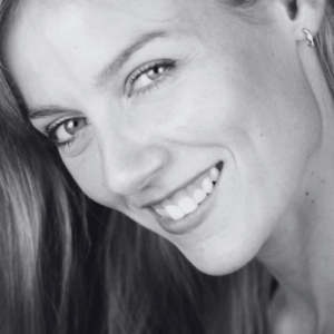 Close up of a smiling woman with long hair tilted head wearing a small hoop earring