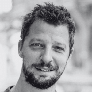 Close up portrait of a smiling man with short dark hair and a trimmed beard looking at the camera
