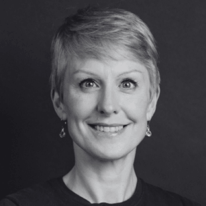 Smiling woman with short hair and drop earrings in a black and white portrait facing the camera