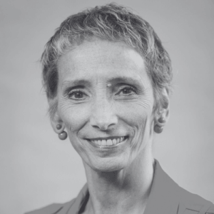 Portrait of a smiling woman with short gray hair wearing small earrings and a blazer looking at the camera black and white photo