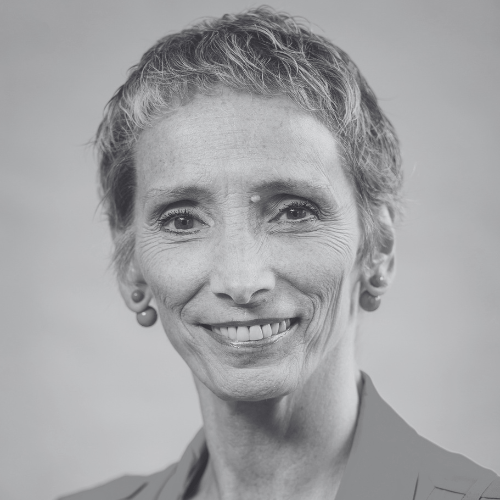 Portrait of a smiling woman with short gray hair wearing small earrings and a blazer looking at the camera black and white photo