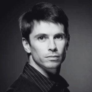 Black and white head and shoulders portrait of a man looking at the camera with a neutral expression