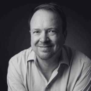Black and white portrait of a smiling man in a collared shirt looking at the camera